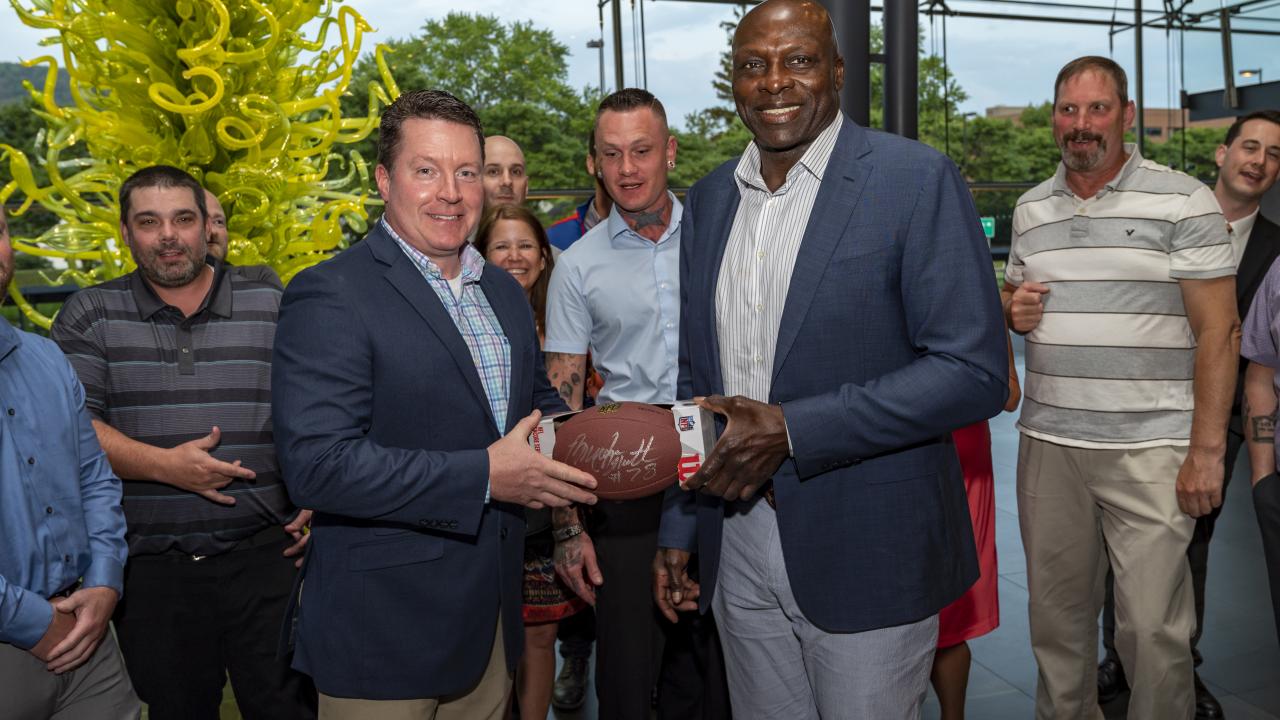 Former NFL and Football Hall of Famer Bruce Smith takes a photo with a group of people at the Corning Museum of Glass