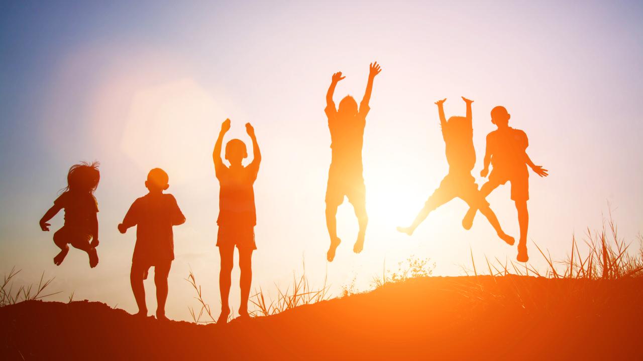 Silhouettes of children jumping in the sunset