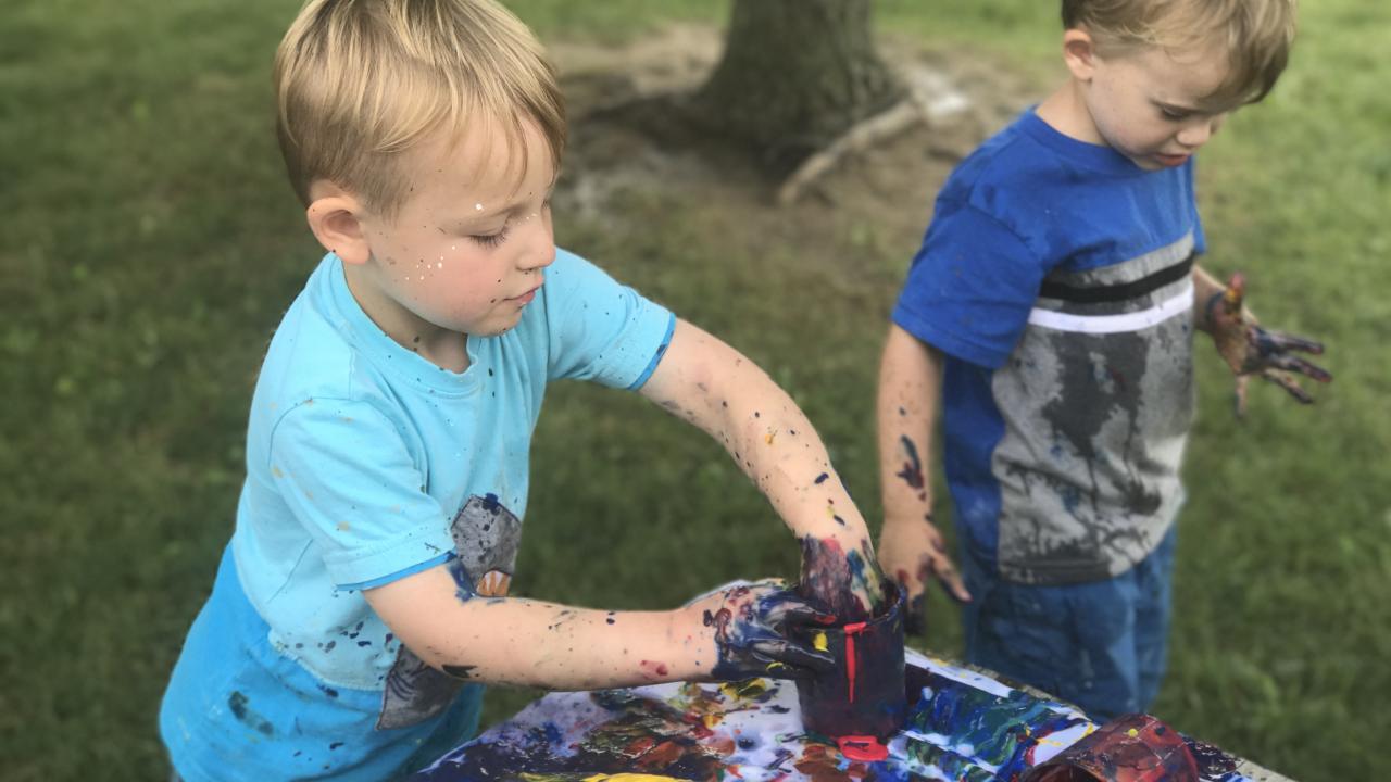 Two young boys painting with their hands during Messy Art Day