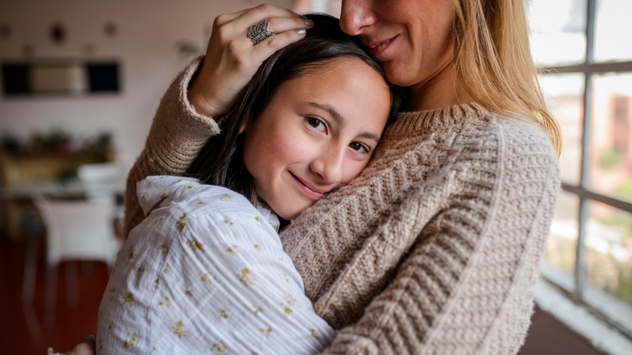 Young girl hugging a woman in a brown sweater