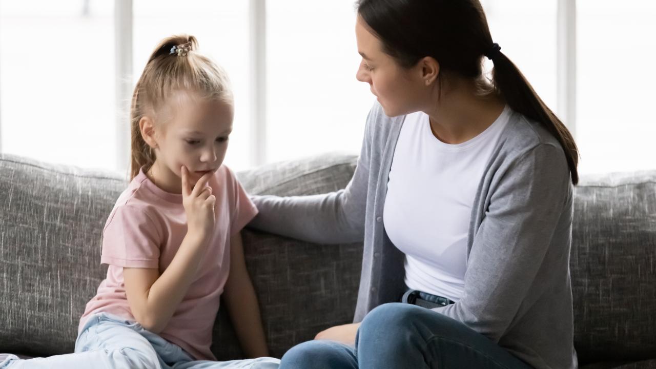 young girl and woman talking on a couch