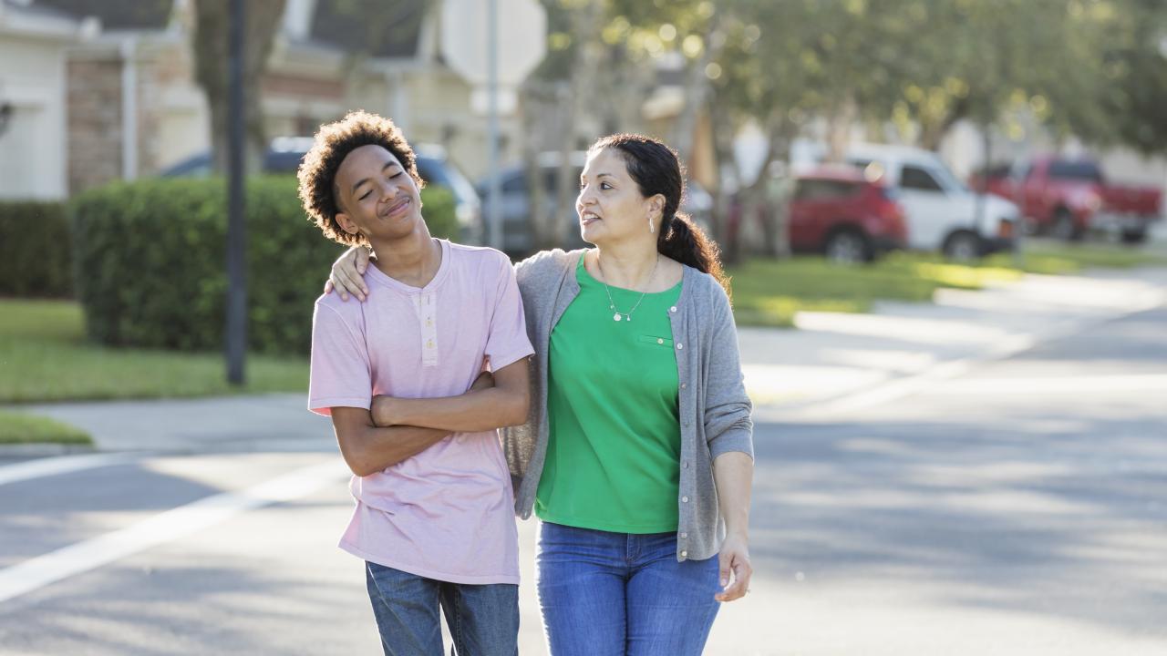 Woman and a teen boy going for a walk through a neighborhood
