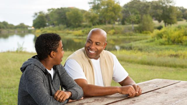 Man sitting next to a boy at a picnic table