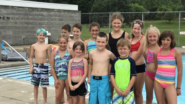 A group of children standing in front of a pool